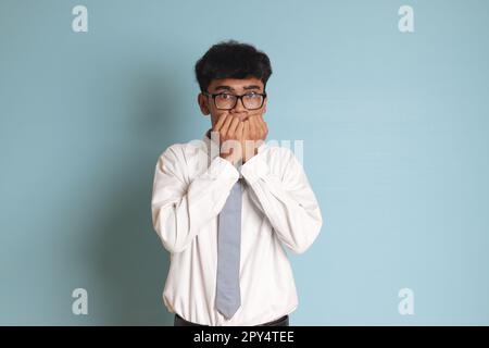 Étudiant de lycée indonésien portant un uniforme de chemise blanc avec une cravate grise couvrant son visage avec les mains. Image isolée sur fond blanc Banque D'Images