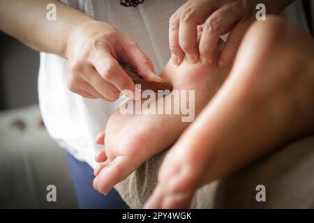 Client recevant un traitement de réflexologie d'acupression avec un bâton de massage à points en bois. Médecine naturelle, réflexologie, massage des pieds d'acupression Banque D'Images