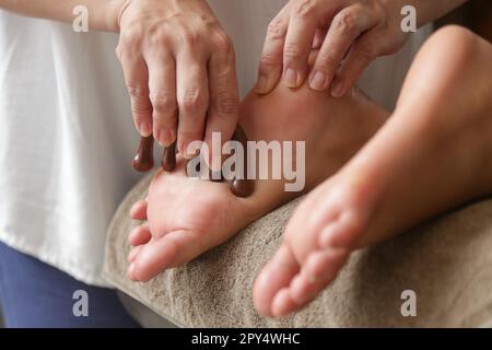 Client recevant un traitement de réflexologie d'acupression avec un bâton de massage à points en bois. Médecine naturelle, réflexologie, massage des pieds d'acupression Banque D'Images