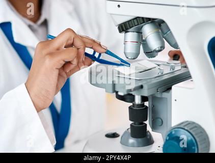 La réponse est sur le point de mentir clair. une scientifique féminine méconnaissable plaçant une lame microscopique sous le microscope tout en travaillant dans un Banque D'Images