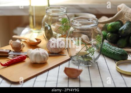 Vider les pots en verre et les ingrédients préparés pour être mis en conserve sur la table Banque D'Images