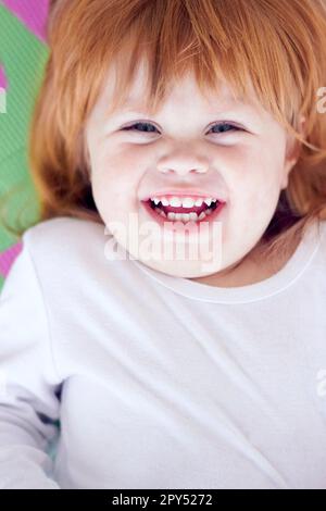 Jeune fille, riant et drôle portrait d'un bébé sur un terrain de parc à la maison avec un sourire. Gingembre bébé, enfant rire et heureux dans une maison avec joie, jeunesse Banque D'Images