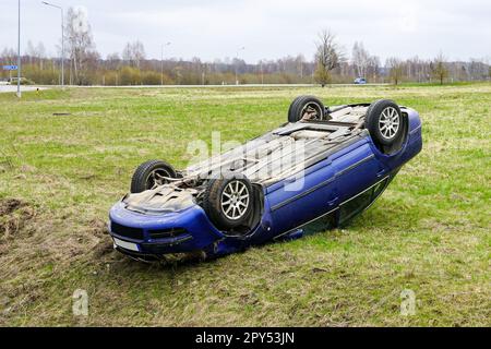 Scène d'accident de voiture, une voiture de tourisme a quitté la route et a renversé avec ses roues vers le haut, véhicule renversé Banque D'Images