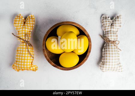 Carte postale blanche de Pâques pour les fêtes, petits pains carrés faits main et œufs jaunes de couleur poulet dans une assiette en bois. Banque D'Images