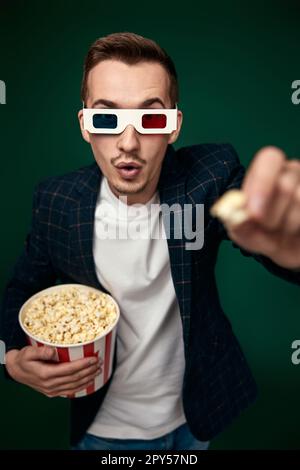 Jeune homme caucasien dans 3D verres mangeant du pop-corn Banque D'Images