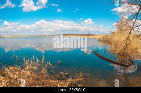 Vieux bateau en bois inondé dans l'eau bleue, le bois de broussailles jaune, et les roseaux, rivière Guiva à Andrushivka, Ukraine Banque D'Images