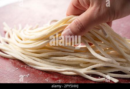 Main d'un homme tenant des nouilles udon fraîches. Banque D'Images