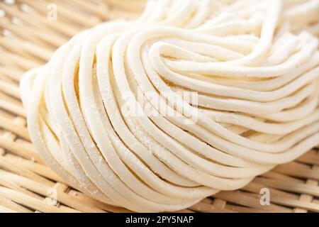 Nouilles udon fraîches dans une passoire de bambou placée sur un fond blanc. Banque D'Images