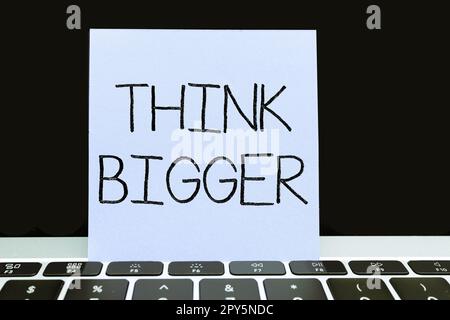 Écriture affichage du texte pensez plus grand. Le concept d'entreprise étant capable de rêver et de visualiser ce que vous pouvez réaliser Banque D'Images