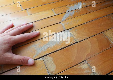 Les anciens parquets rayés doivent être entretenus. le parquet est endommagé par des rayures résultant d'une utilisation prolongée. Les mains du maître sont endommagées par le sol Banque D'Images