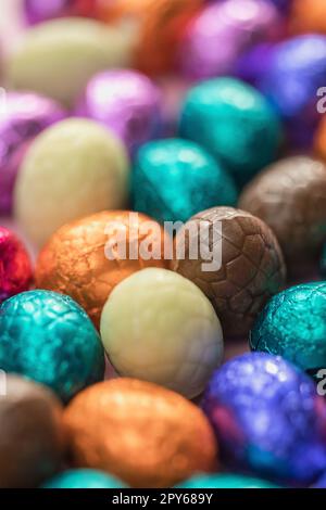 Grande pile d'œufs de pâques en chocolat enveloppés de couleurs, concept de Pâques festif brillant, macro de bonbons en gros plan joyeuses pâques Banque D'Images