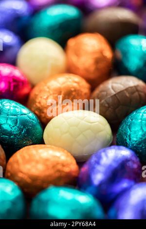 Grande pile d'œufs de pâques en chocolat enveloppés de couleurs, concept de Pâques festif brillant, macro de bonbons en gros plan joyeuses pâques Banque D'Images