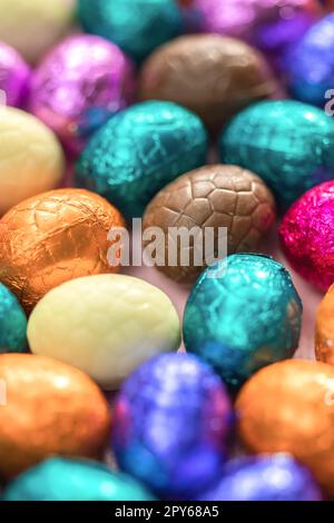 Grande pile d'œufs de pâques en chocolat enveloppés de couleurs, concept de Pâques festif brillant, macro de bonbons en gros plan joyeuses pâques Banque D'Images