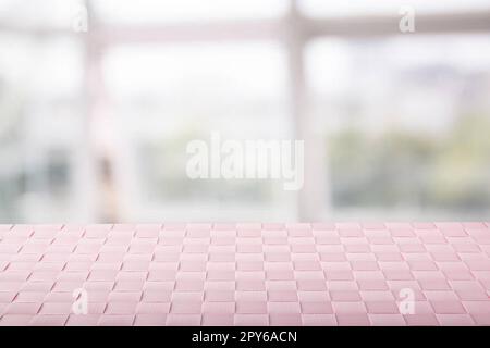 Produit de table vide. Gros plan d'une nappe ou d'une serviette rose vide sur une table sur un arrière-plan abstrait flou de fenêtres lumineuses. Modèle pour votre montage de présentation de produits et de produits alimentaires. Banque D'Images