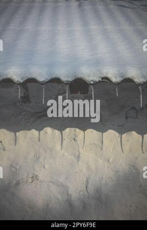 Gros plan sur les glaces suspendues au toit recouvert de neige concept photo Banque D'Images