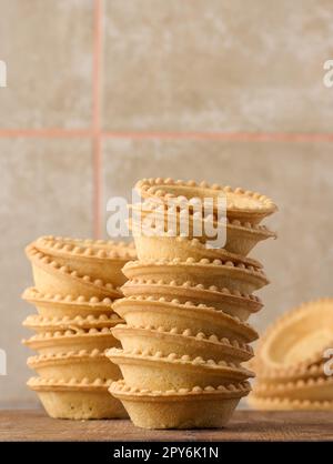 Pile de paniers ronds de canapés cuits vides sur un panneau en bois, tartelettes rondes vides Banque D'Images