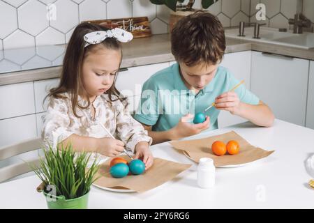 Portrait de studily joyful deux petits enfants garçon et fille, pinceau colorant les oeufs de Pâques. Salon de vacances en famille Banque D'Images