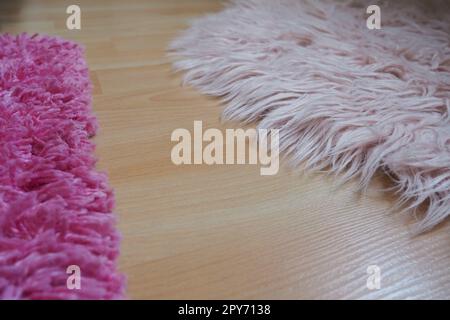 Tapis épais rose sur sol stratifié beige. Intérieur féminin pour une chambre ou une chambre d'une fille ou d'une femme. Décoration intérieure dans des tons roses. Le sol est stratifié. Le rôle des acariens dans les allergies. Banque D'Images