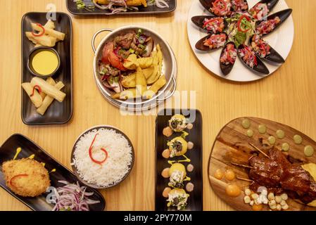 Ensemble de plats péruviens colorés avec moules fraîches, anticuchos grillés, riz blanc, lomo saltado, causa lima, yucca frit Banque D'Images