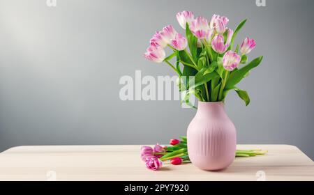 Un bouquet de tulipes dans vase rose debout sur la table en bois Banque D'Images