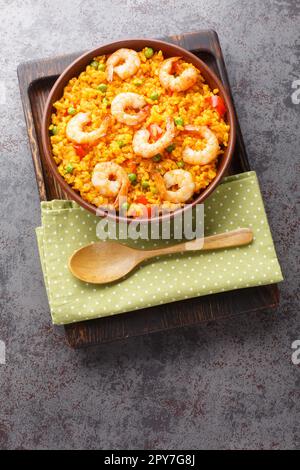 Riz jaune espagnol savoureux et crevettes avec légumes et épices sur l'assiette de la table. Vue verticale du dessus Banque D'Images