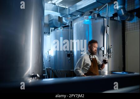 Propriétaire d'usine de brasserie examinant la qualité de la bière artisanale Banque D'Images