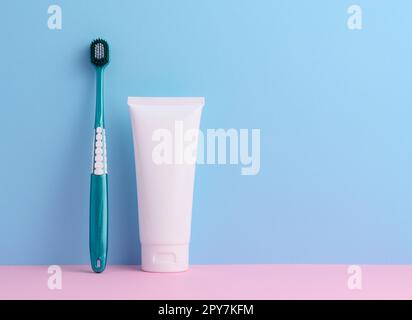 Brosse à dents et tube de dentifrice en plastique blanc sur fond bleu Banque D'Images