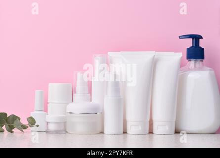 Tubes, bocaux et récipients en plastique blanc pour produits cosmétiques sur fond rose, publicité et marquage des produits Banque D'Images
