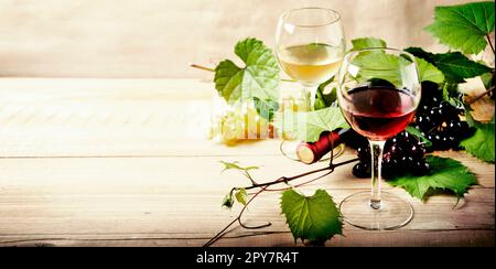 Verre de vin rouge et blanc, bouteille et vigne sur table en bois d'époque. Banque D'Images