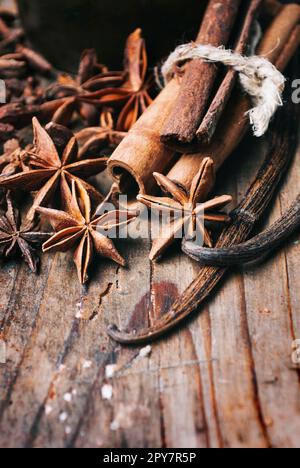 Gros plan de bâtonnets de graines d'anis, de vanille et de cannelle sur une table en bois rustique. Banque D'Images