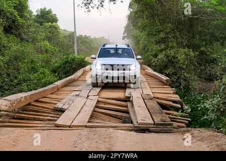 4x4 blanc traversant un pont en bois sur la route de Transpantaneira à travers le nord du Pantanal, le matin d'une brumeuse matinée, Mato Grosso, Brésil Banque D'Images