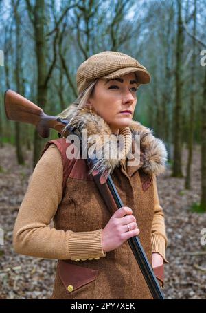 Une femme de plus de trente ans qui tiriez sur des bois à la fin du printemps avec un fusil de chasse se préparant à tirer sur des pigeons Banque D'Images