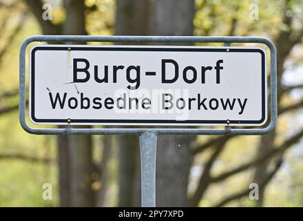 PRODUCTION - 03 mai 2023, Brandenburg, Burg: Un panneau de rue en allemand et sorabe 'Burg-Dorf Wobsedne Borkowy' se dresse près du village Spreewald de Burg. À la suite de la lettre des enseignants au sujet des incidents extrémistes de droite dans leur école du Spreewald, les autorités veulent répondre à ces allégations. Les éducateurs se sont également plaints du manque de soutien de la part des administrateurs scolaires, des conseils scolaires et des politiciens. La critique est en cours d'examen et des pourparlers sont en cours avec les personnes concernées, a déclaré le Ministère de l'éducation de Potsdam mardi lorsqu'on leur a demandé. « L'école a besoin de calme et bien sûr Banque D'Images
