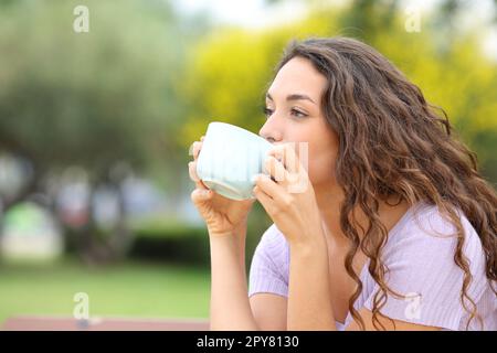 Femme buvant du café sur un banc Banque D'Images