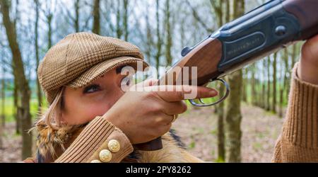 Une femme de plus de trente ans qui tiriez sur des bois à la fin du printemps avec un fusil de chasse se préparant à tirer sur des pigeons Banque D'Images