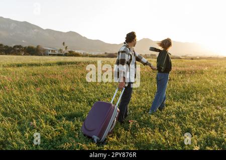 Un jeune couple épris inspiré regarde le plan de vie à l'avenir. Ils sont debout avec une valise et ukulele, tenant les mains. Recherche d'une nouvelle homela Banque D'Images