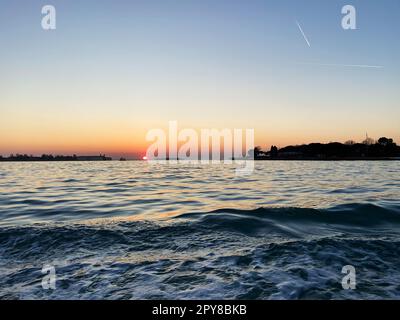 le soleil se couche sous la surface de l'eau à l'horizon Banque D'Images