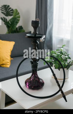 Bol à narguilé de shisha avec des charbons chauds rouges et du tabac artisanal. Un narguilé moderne avec du charbon de coco pour se détendre et fumer dans le salon. Banque D'Images