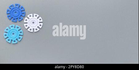 Détails multicolores en forme de flocons de neige du designer pour enfants sur fond gris. Disques en plastique blanc, bleu clair et bleu marine pour le développement de la motricité fine des doigts Banque D'Images