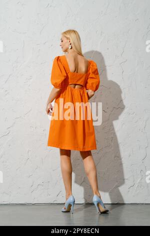 Vue arrière de la femme élégante dans la robe orange lâche Banque D'Images