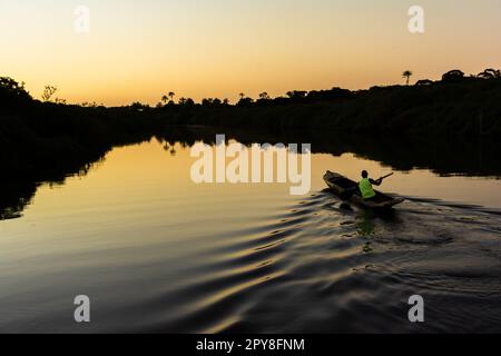 Aratuipe, Bahia, Brésil - 31 août 2018 : un pêcheur pagayant son canoë sur le fleuve Jaguaripe, ville d'Aratuipe, au coucher du soleil. Banque D'Images