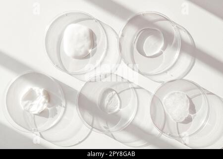 Différents produits cosmétiques échantillons de gel dans des boîtes de Petri de laboratoire sur fond blanc Banque D'Images