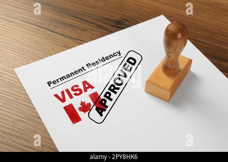 Document avec visa de résidence permanente approuvé au Canada et timbre sur table en bois Banque D'Images
