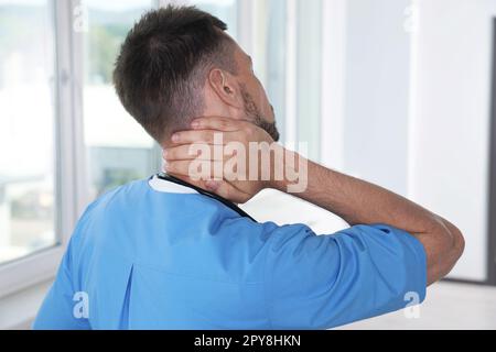 Un médecin exténué frottant le cou à l'hôpital, vue arrière Banque D'Images