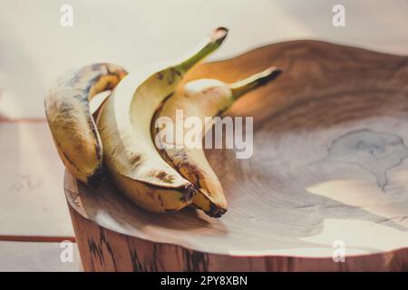 Gros plan des bananes mûres couchées sur une souche de bois sous la lumière du soleil concept photo Banque D'Images