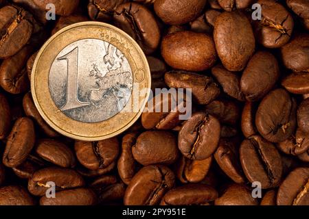 Gros plan sur les grains de café torréfiés et une pièce en euros Banque D'Images