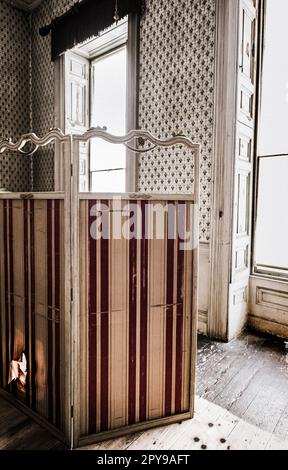 Un panneau de garniture vintage déchiré rayé ou un écran changeant dans une maison abandonnée Banque D'Images