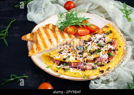 Omelette frite farcie à la saucisse, aux tomates, aux légumes verts et au fromage. Délicieux petit déjeuner facile Banque D'Images