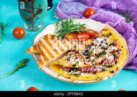 Omelette frite farcie à la saucisse, aux tomates, aux légumes verts et au fromage. Délicieux petit déjeuner facile Banque D'Images