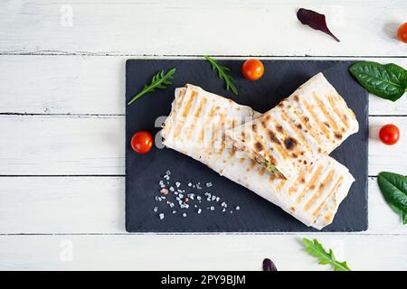 Délicieux sandwich au poulet shawarma avec salade et fromage sur fond de bois Banque D'Images